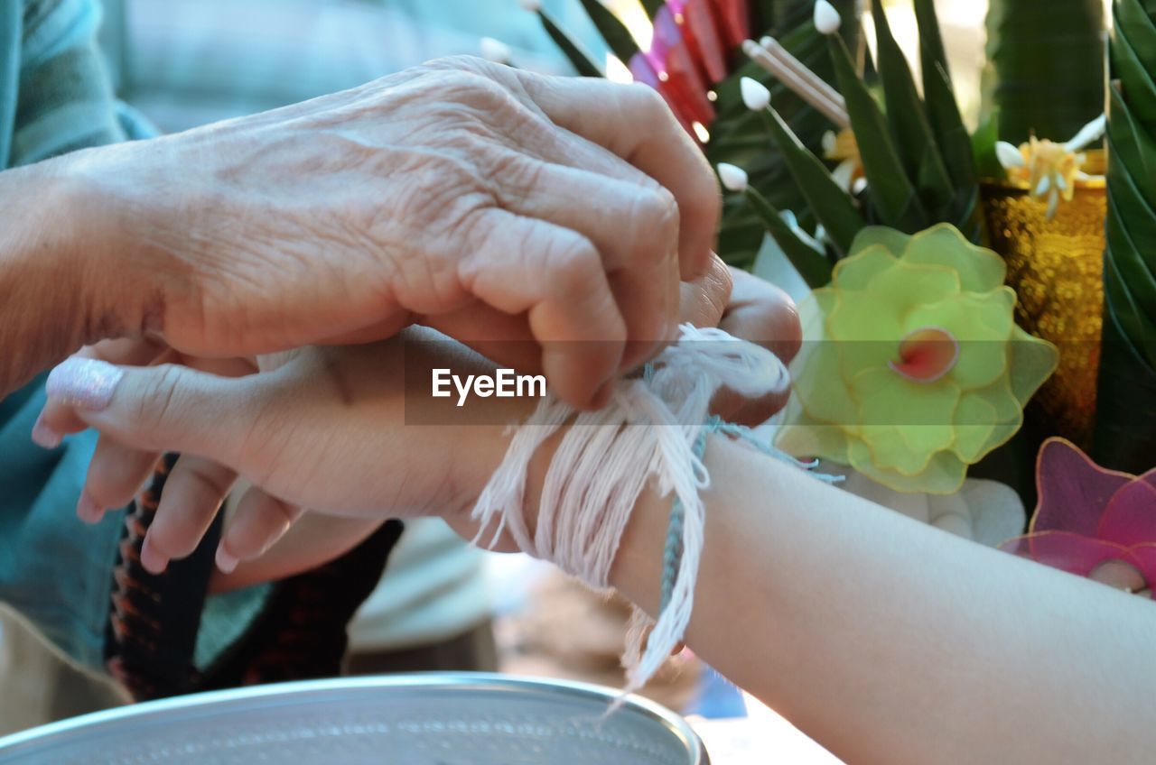 Cropped image of female tying string in woman hand