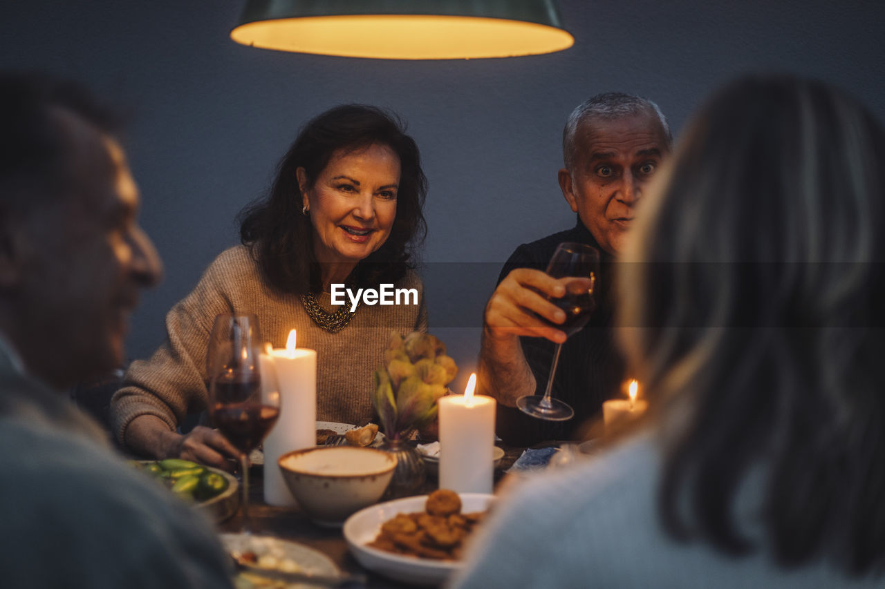 Smiling retired woman enjoying dinner with friends at party