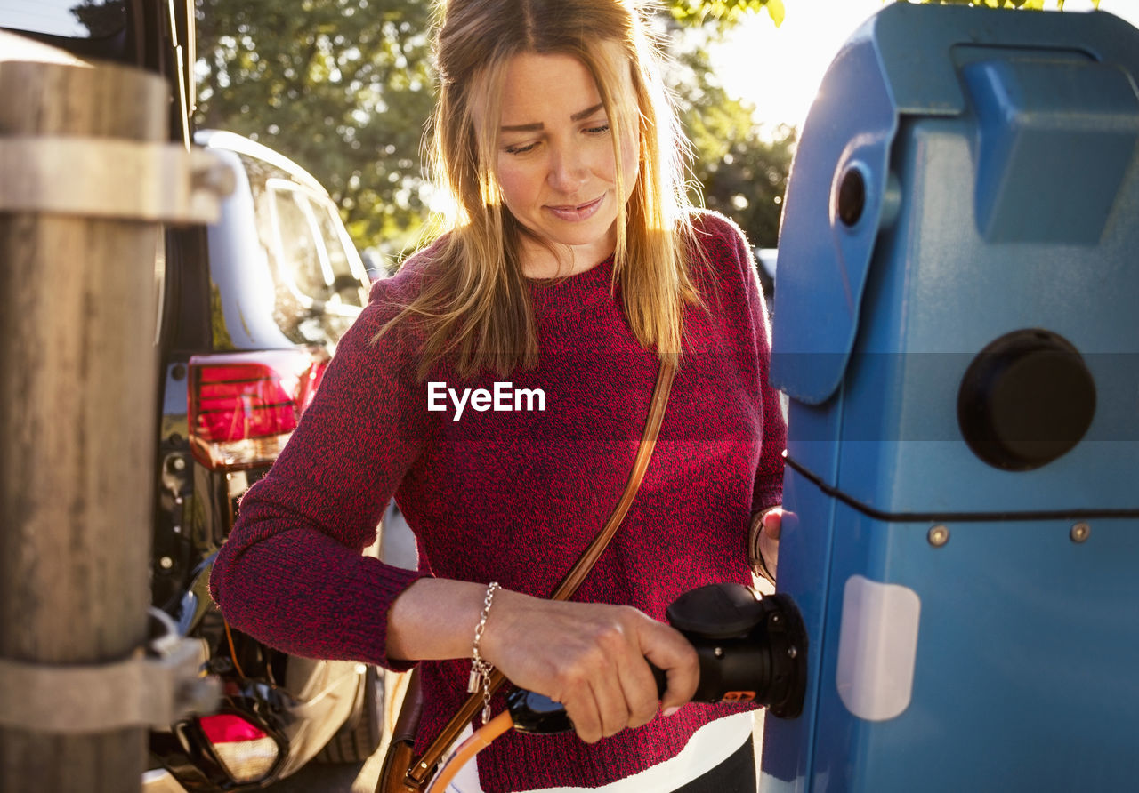 Mature woman plugging cable at station