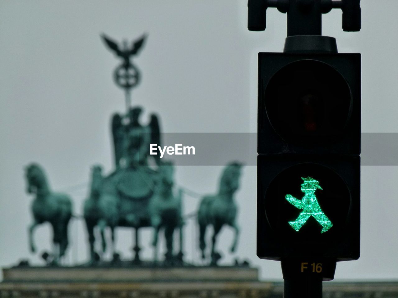 Close-up of pedestrian sign against sculpture