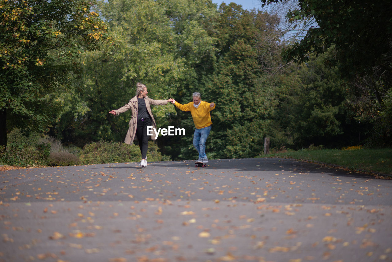 rear view of woman walking on road against trees