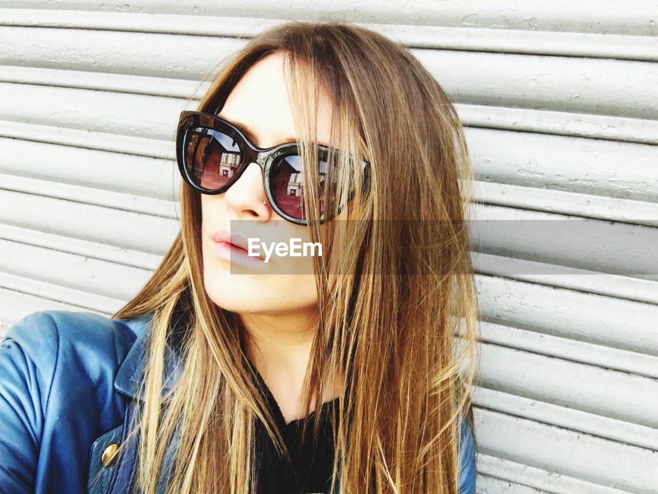 Close-up of woman looking away against store shutter