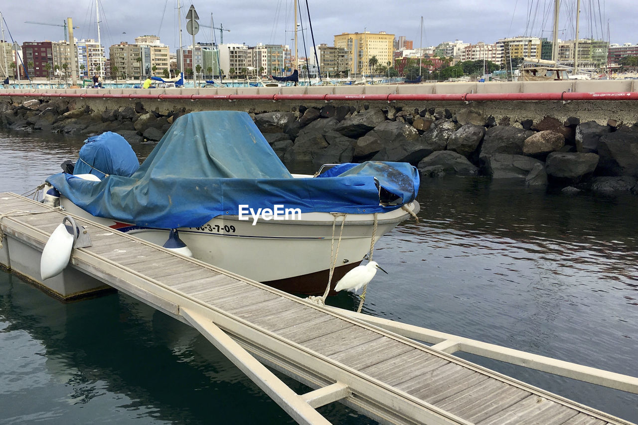 BOATS MOORED IN RIVER AGAINST BUILDINGS