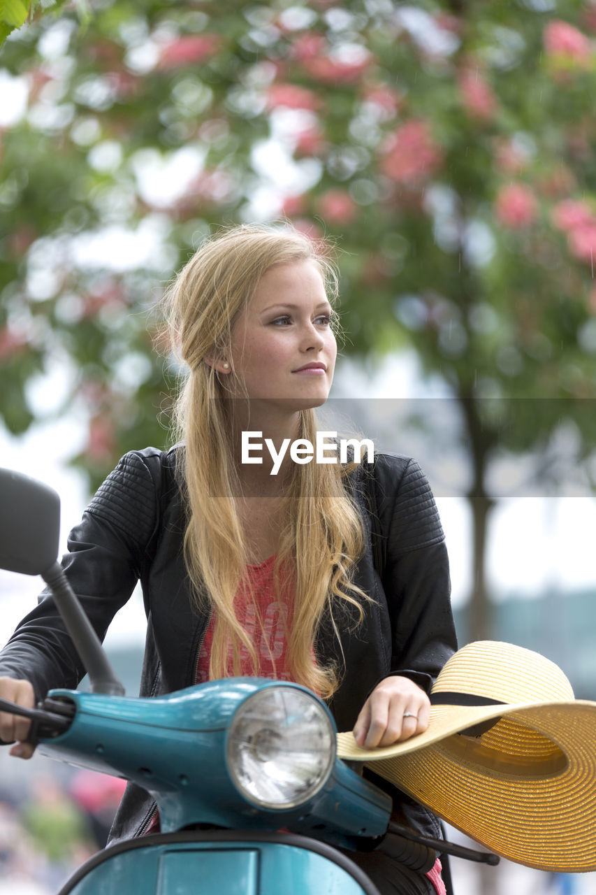 Woman looking away while sitting on motor scooter