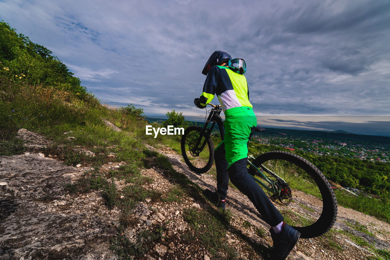 Mountain biker carries a bicycle in a forested landscape of summer mountains. mtb track for cycling