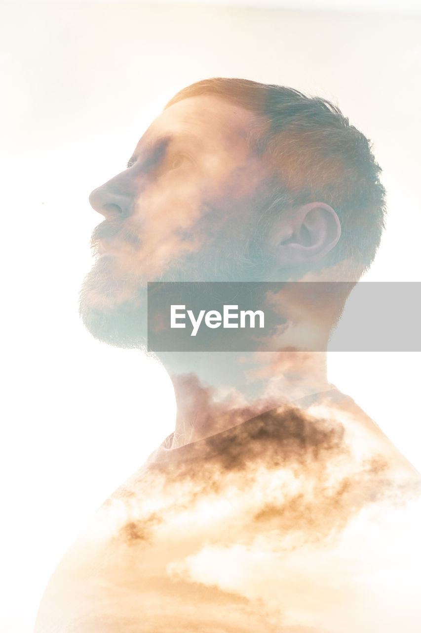 Double exposure of man and clouds against white background