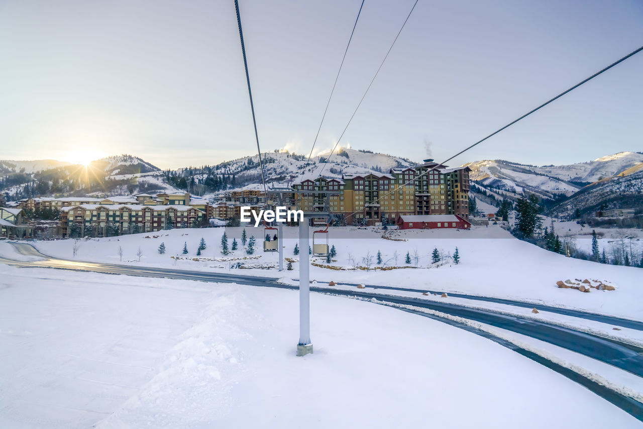 SNOW COVERED BUILDINGS AND MOUNTAIN AGAINST SKY