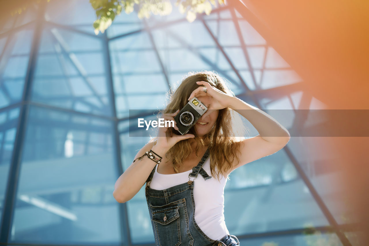 Young woman taking picture with camera in city