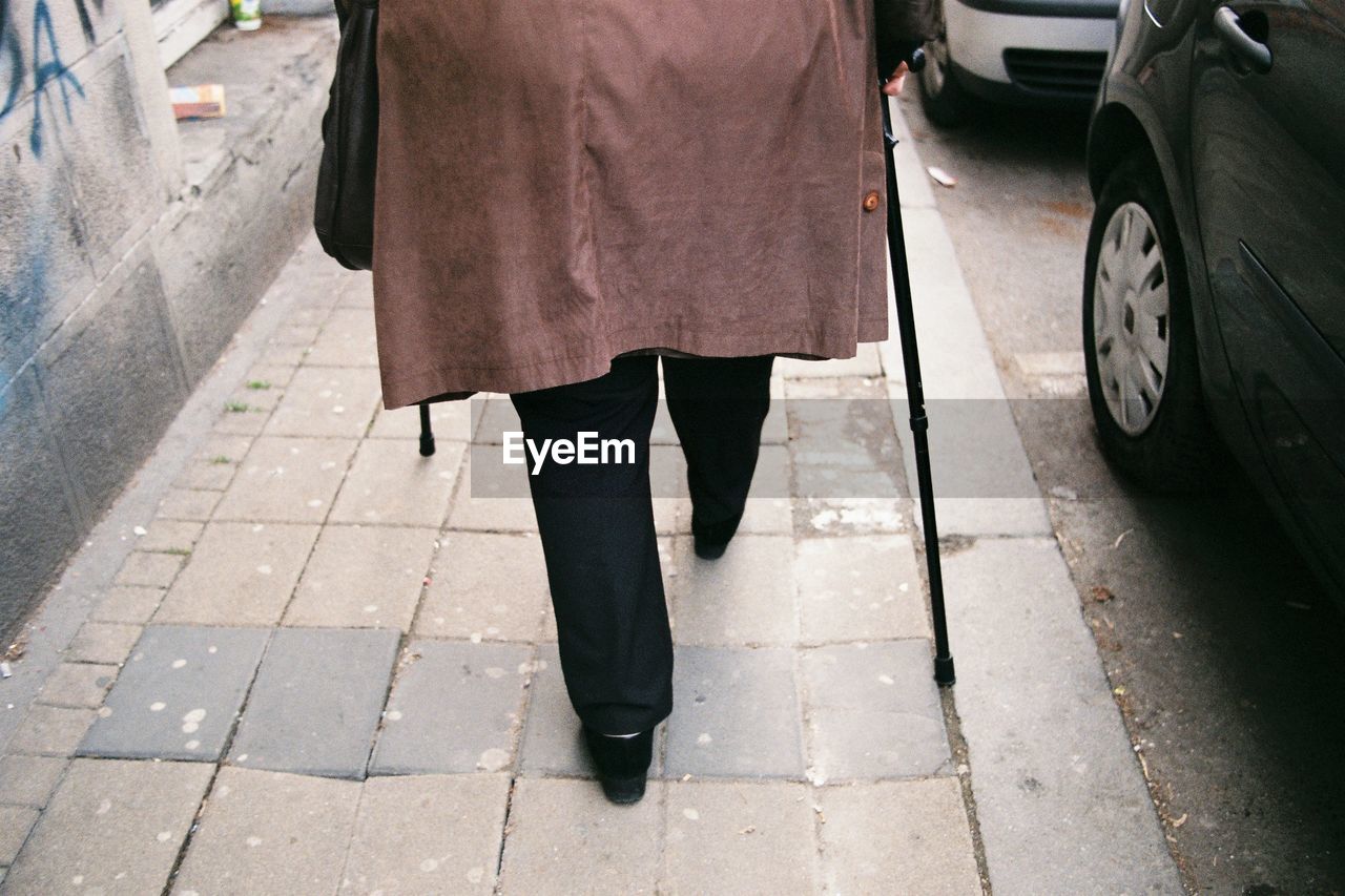 Low section of woman walking on sidewalk in city