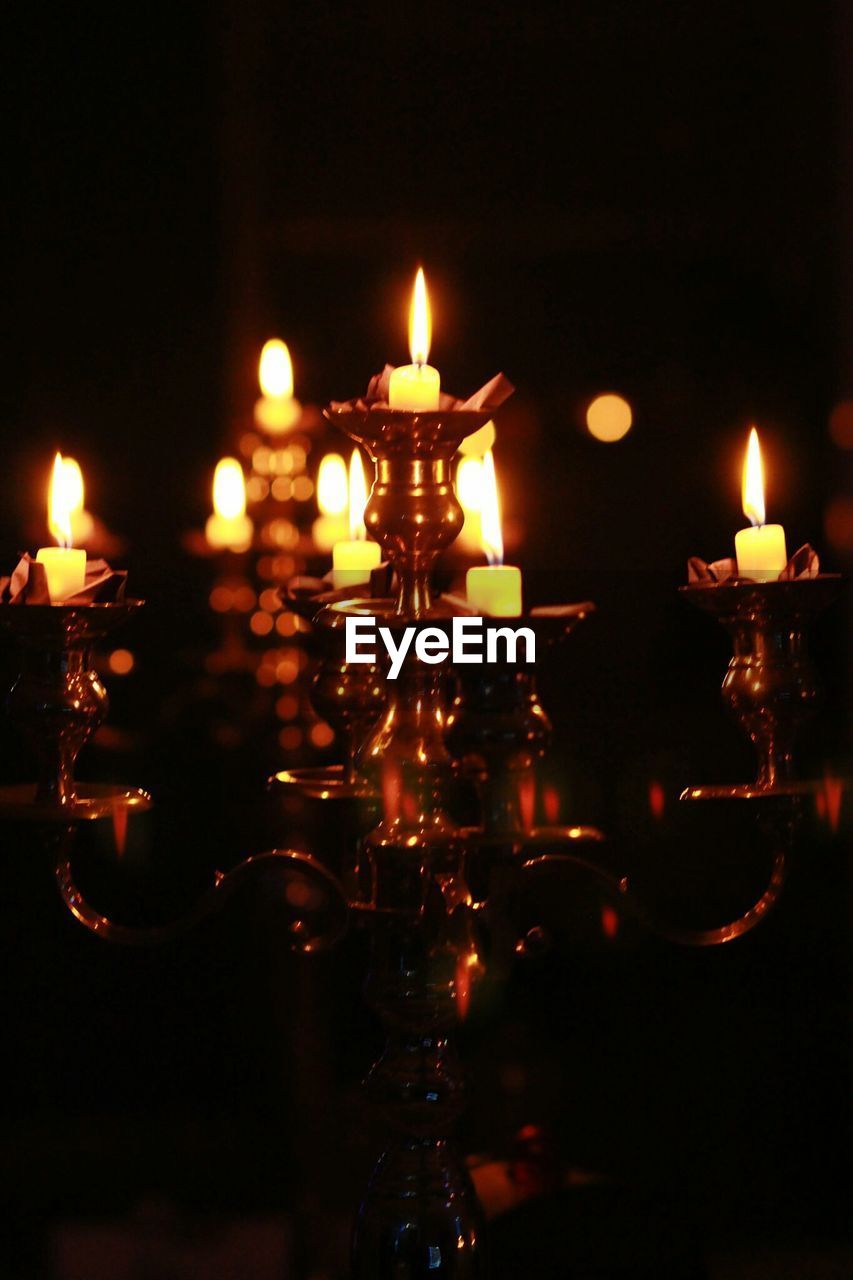 Illuminated candles on candlestick holder in darkroom