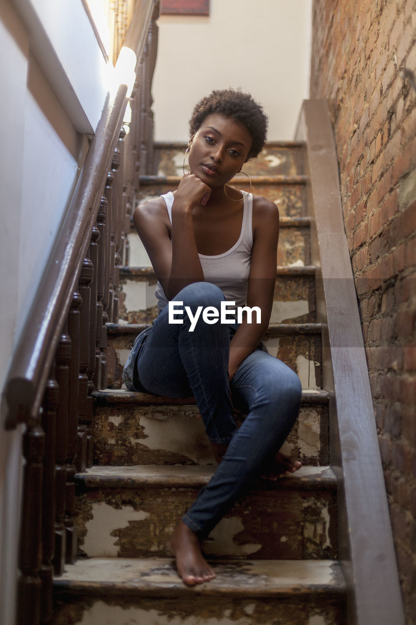 Portrait of a young woman sitting in a staircase