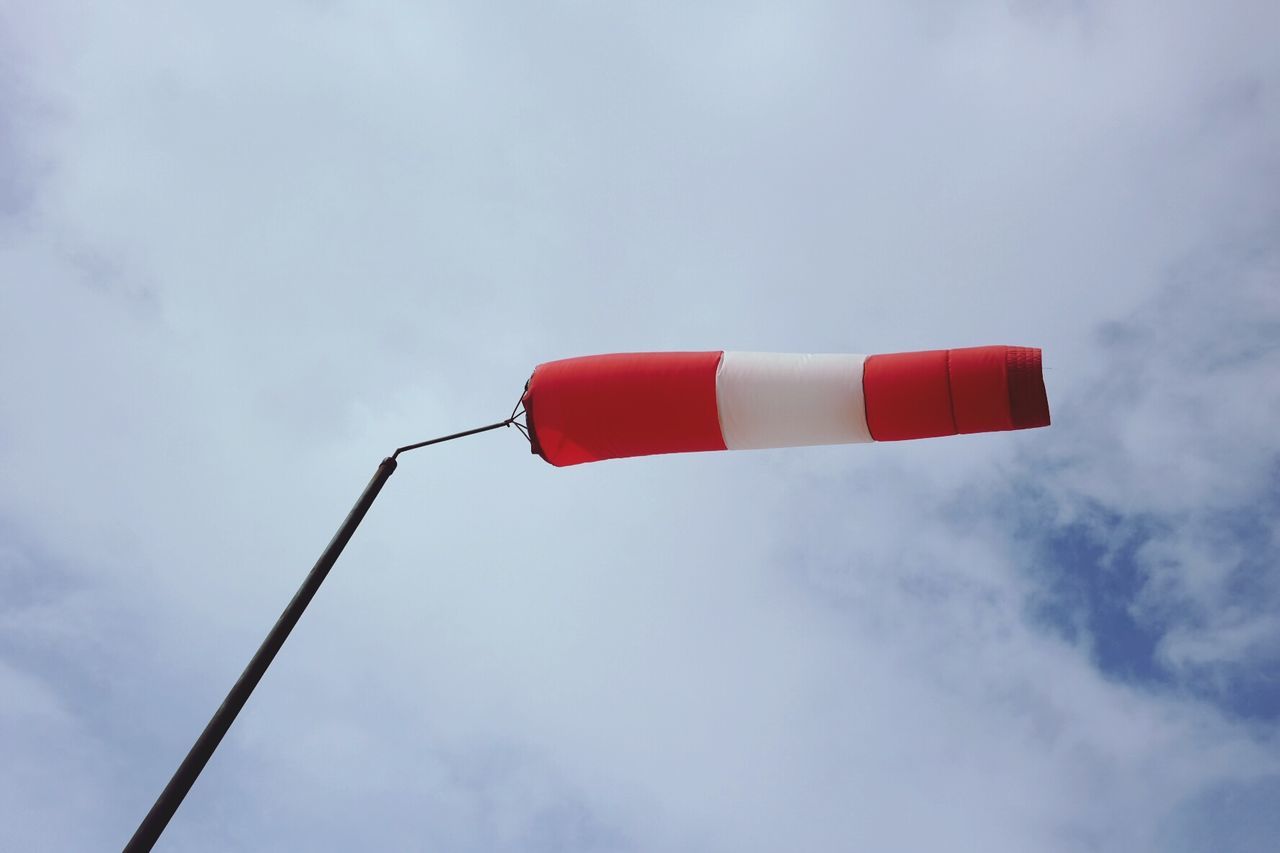 Low angle view of windsock flying against cloudy sky