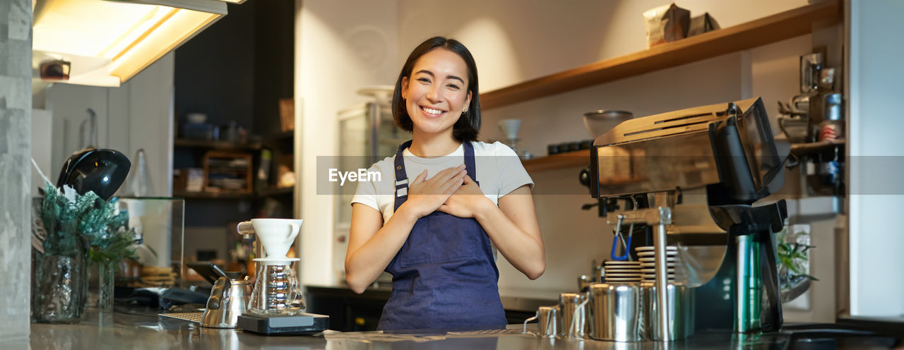 portrait of young woman using mobile phone while sitting on table at home