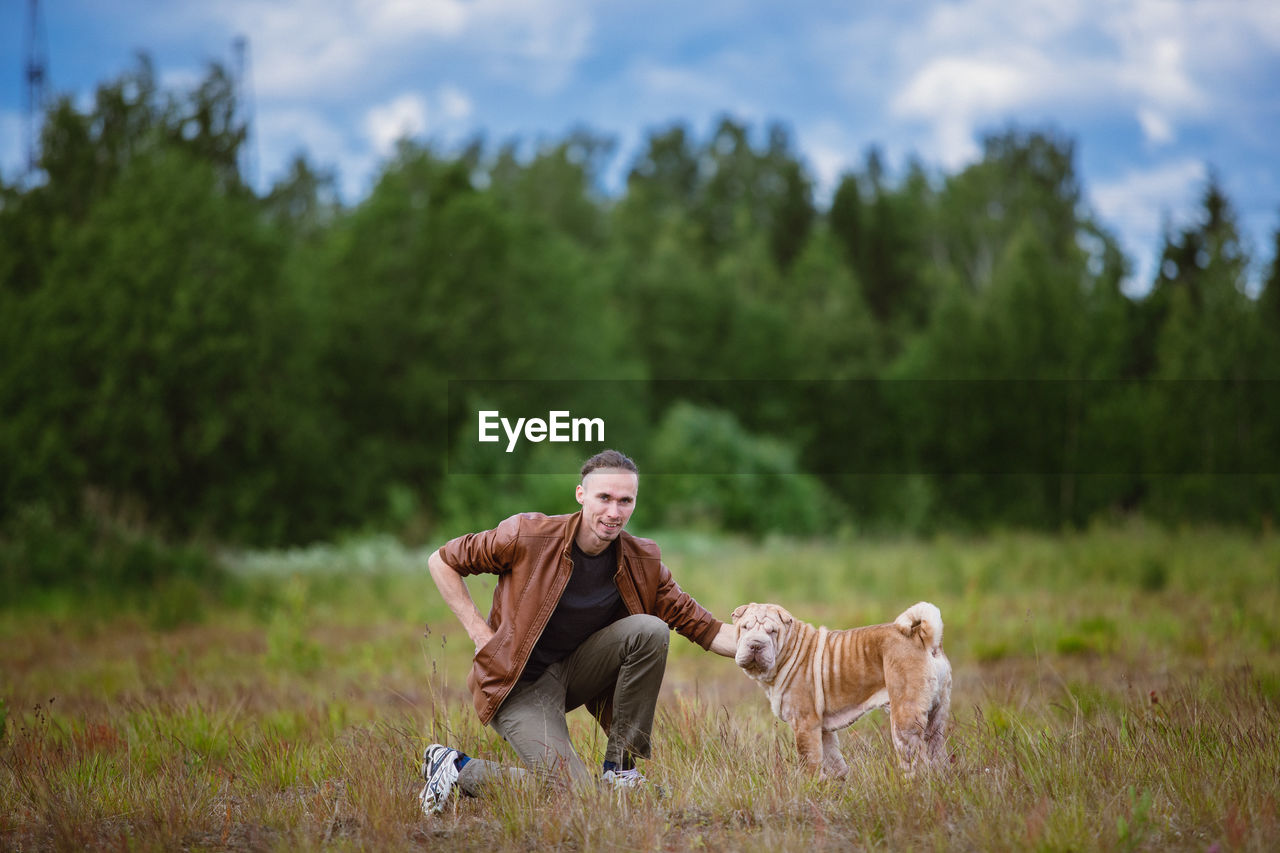 Full length of man with dog on field