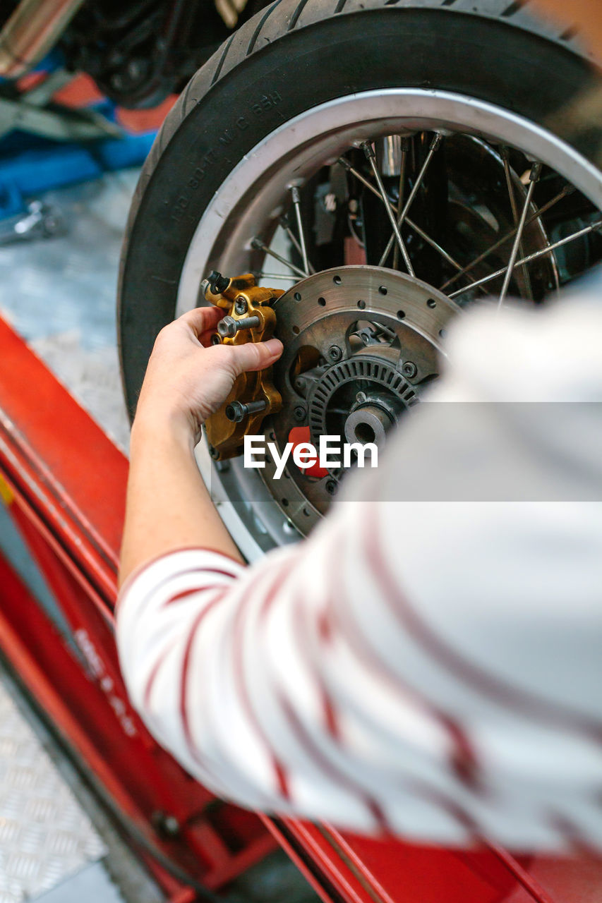 Mechanic woman changing caliper brake system in motorbike wheel