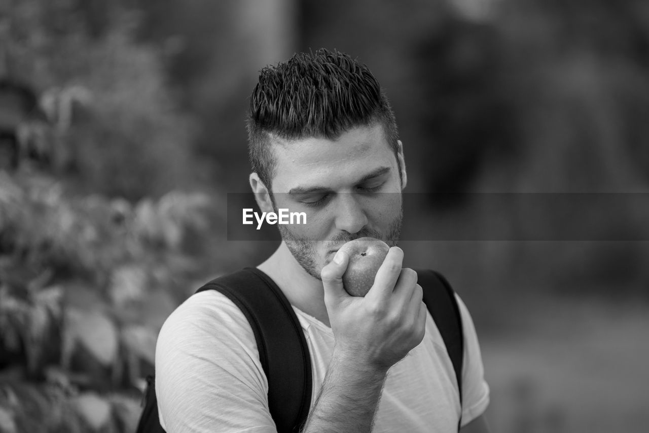Young man holding apple standing outdoors