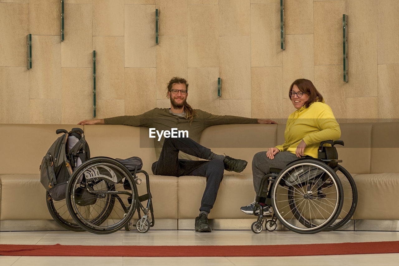 Portrait of smiling couple sitting on wheelchair