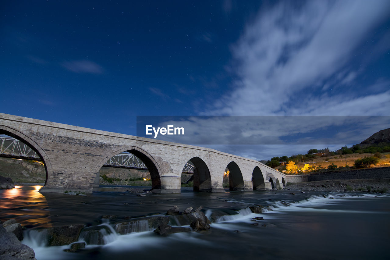 Bridge over river against sky at night