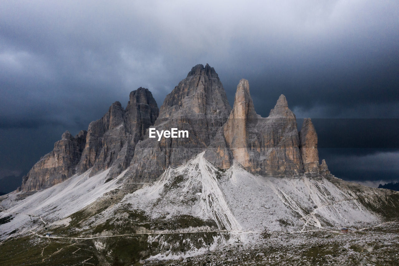Drei zinnen in the dolomites mountains with upcoming thunderstorm above.