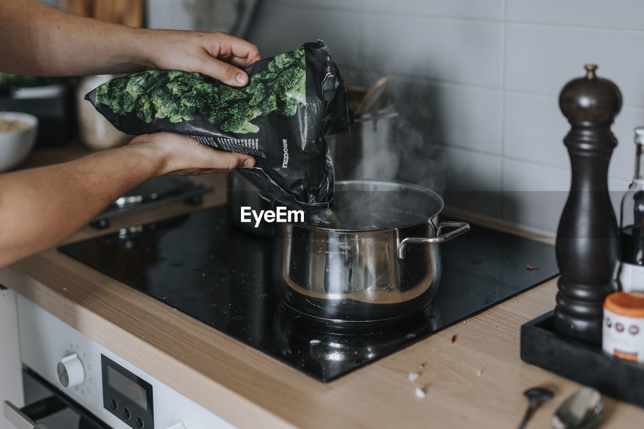 Woman's hands putting vegetables in saucepan