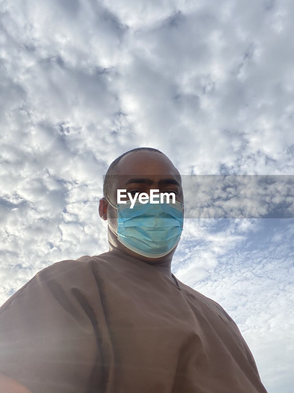 LOW ANGLE VIEW OF MAN WITH UMBRELLA AGAINST SKY