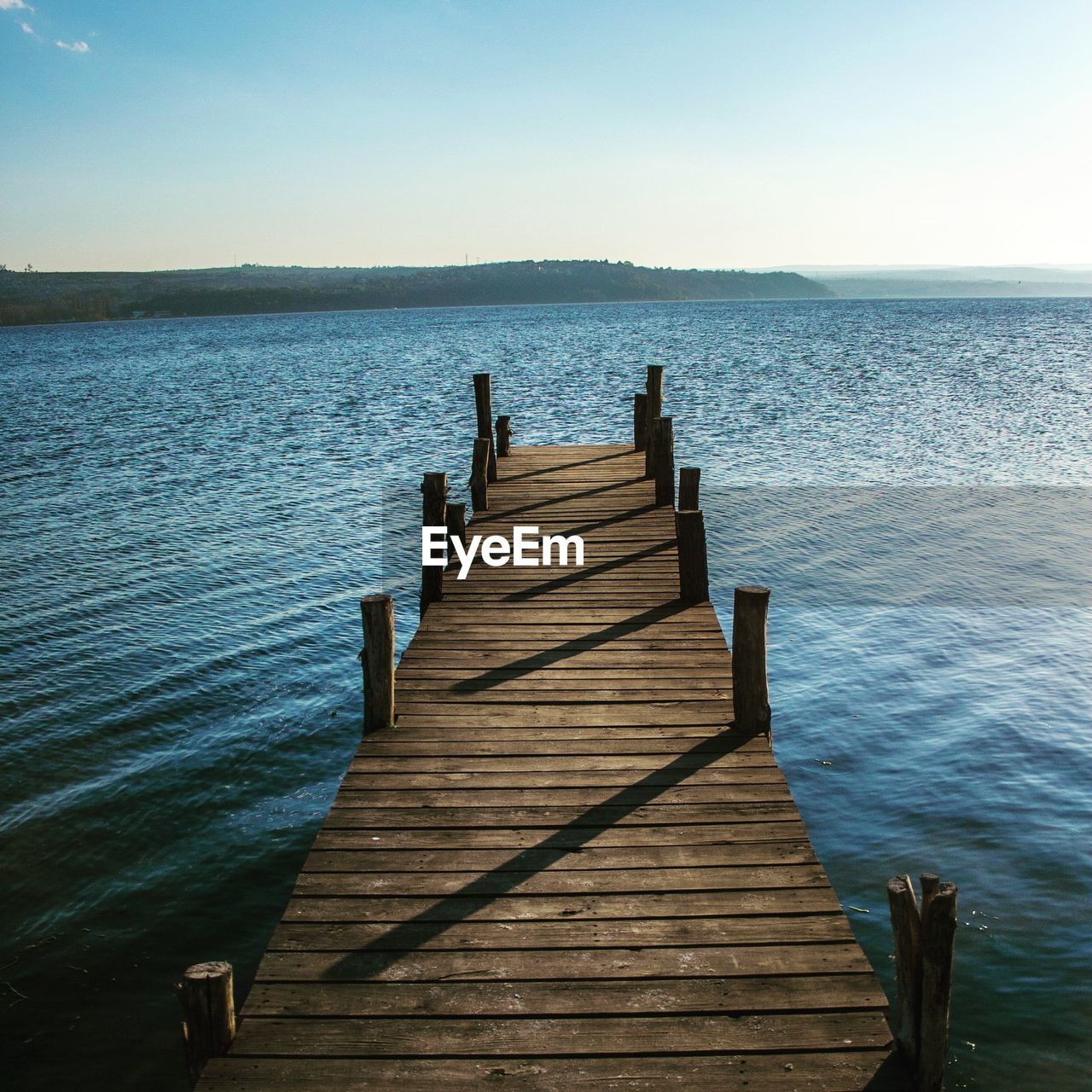 Wooden pier over sea against clear sky