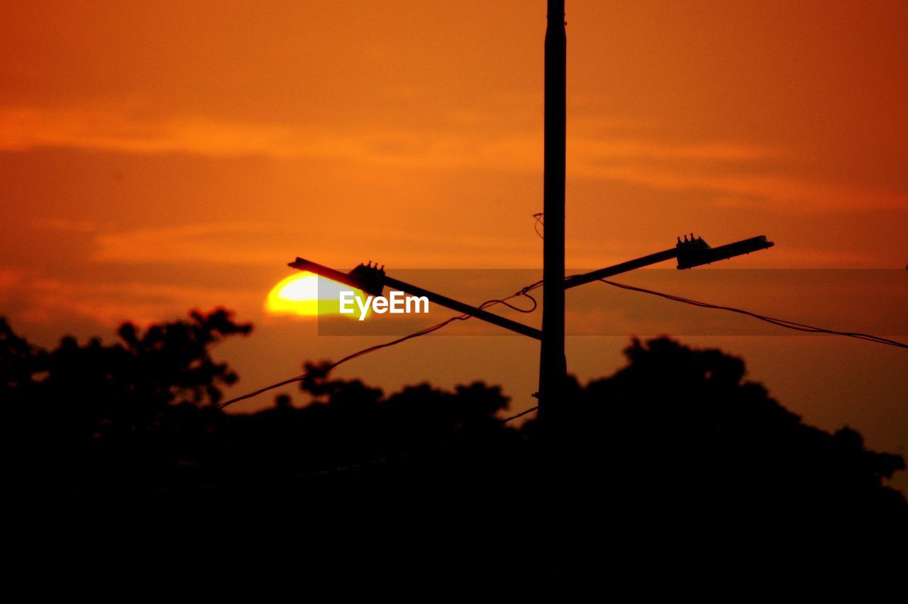 Silhouette street light against orange sunset sky