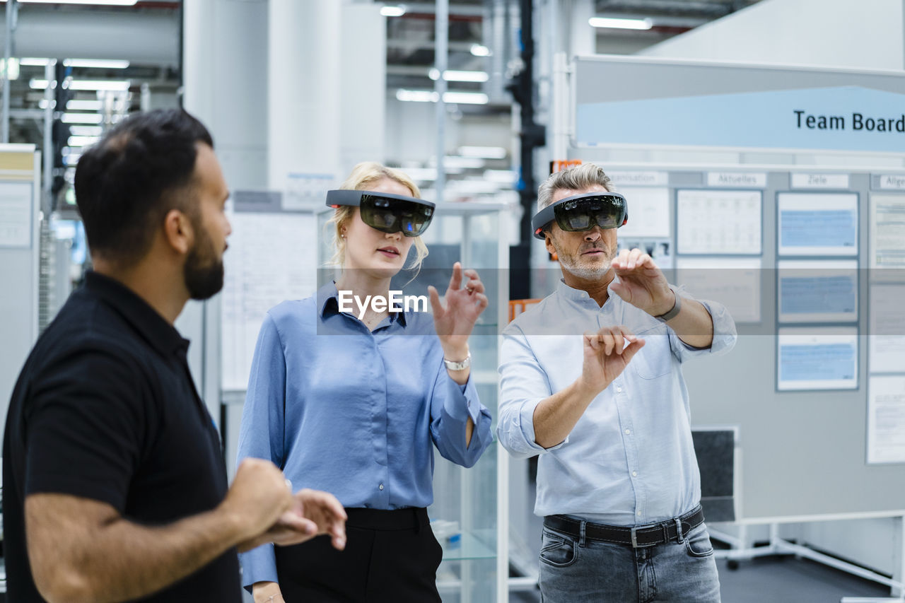 Coworkers using augment reality glasses at electrical industry