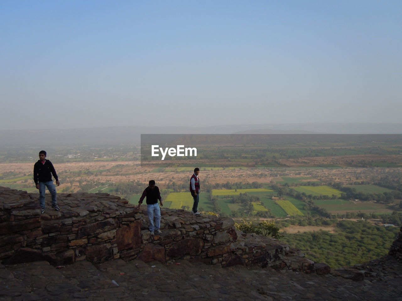 REAR VIEW OF MAN STANDING ON LANDSCAPE AGAINST SKY