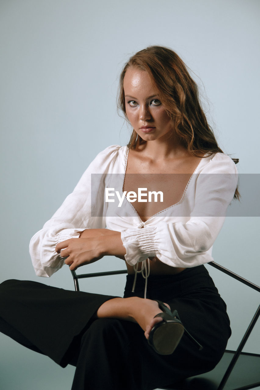 Portrait of a young woman sitting against white background