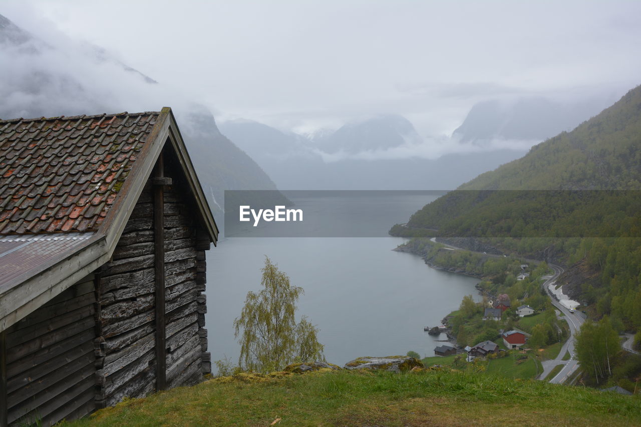 Houses by lake and mountains against sky