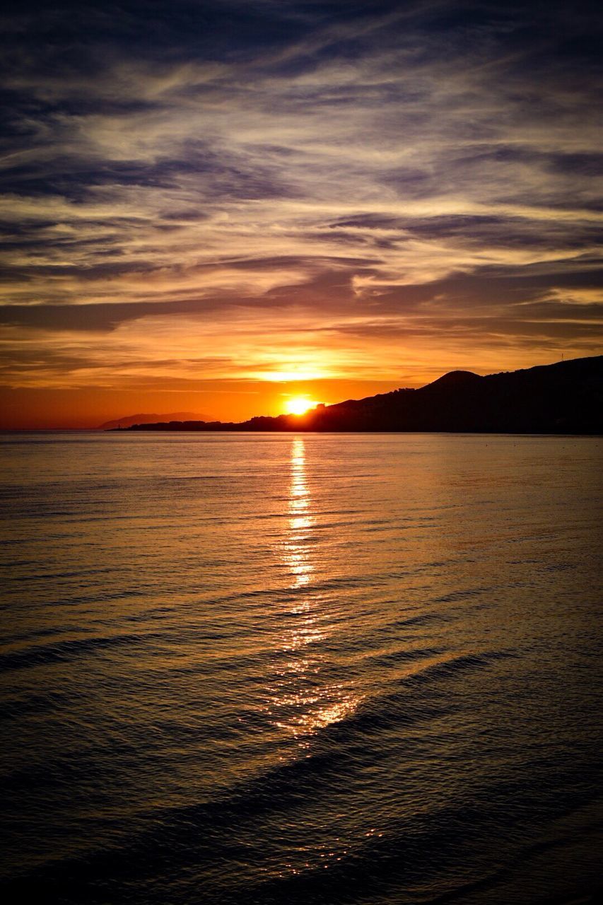 Scenic view of sea against dramatic sky during sunset