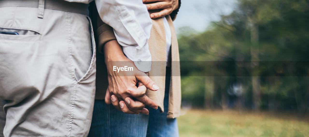 MIDSECTION OF WOMAN HOLDING HANDS