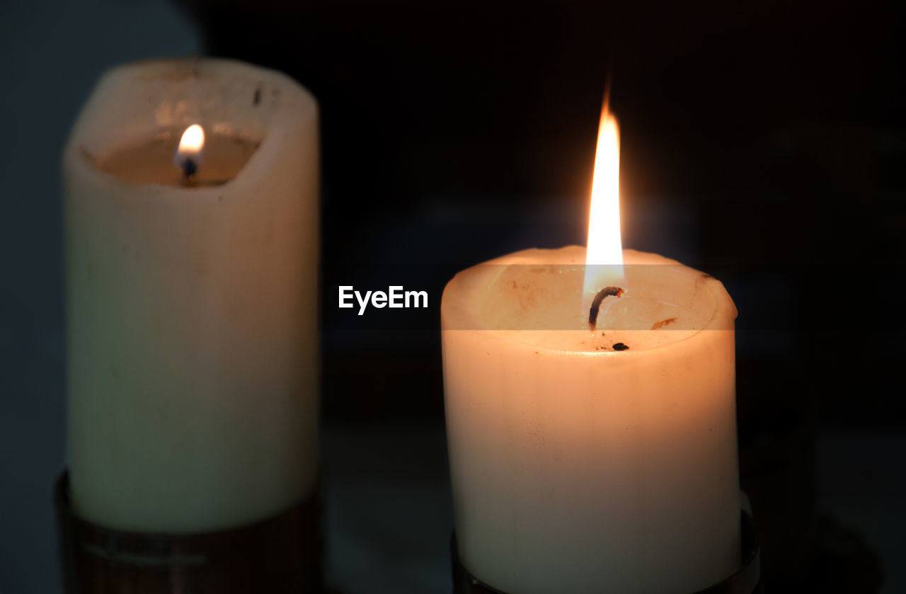 CLOSE-UP OF LIT CANDLE IN THE DARK