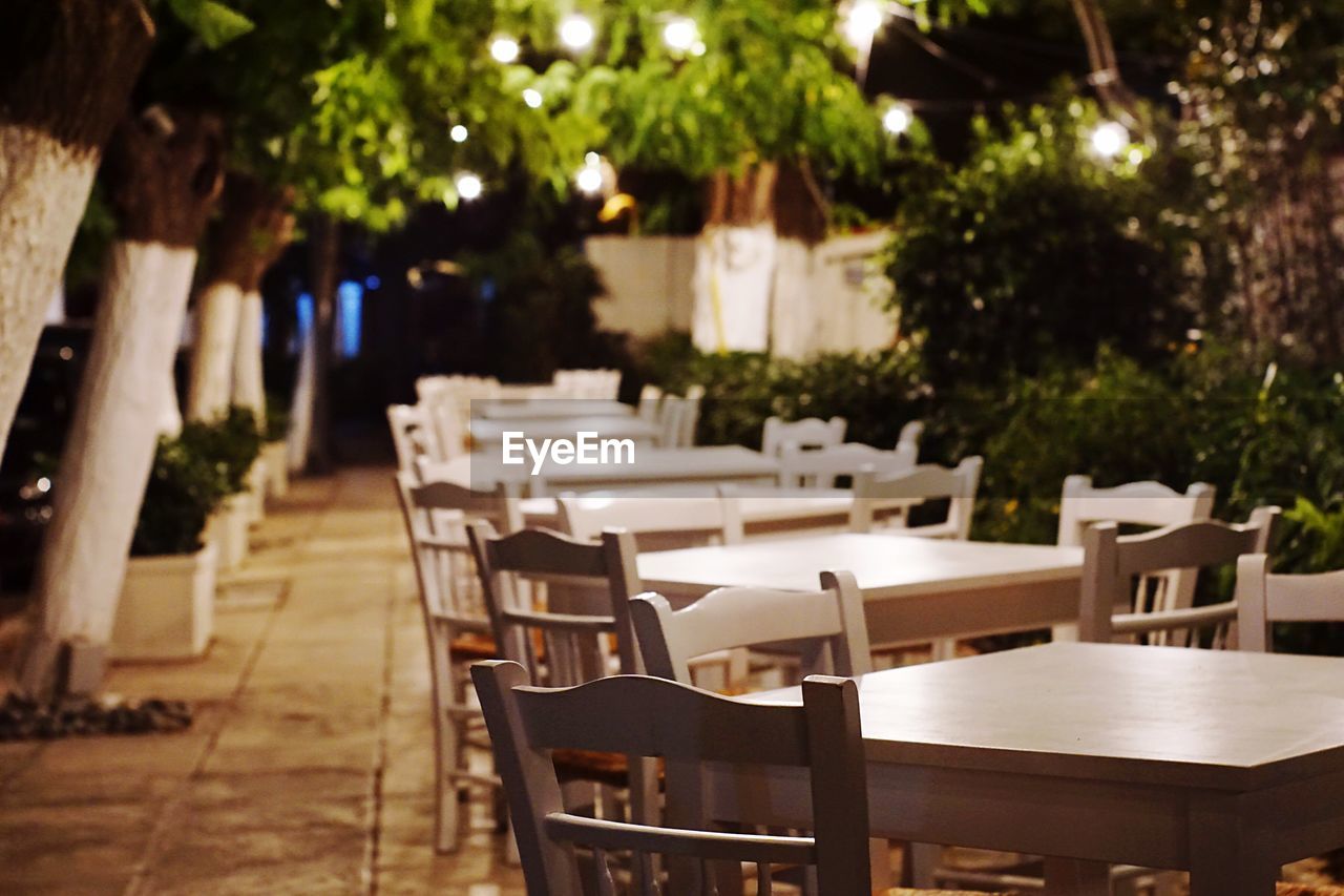 Empty chairs and tables on sidewalk at restaurant