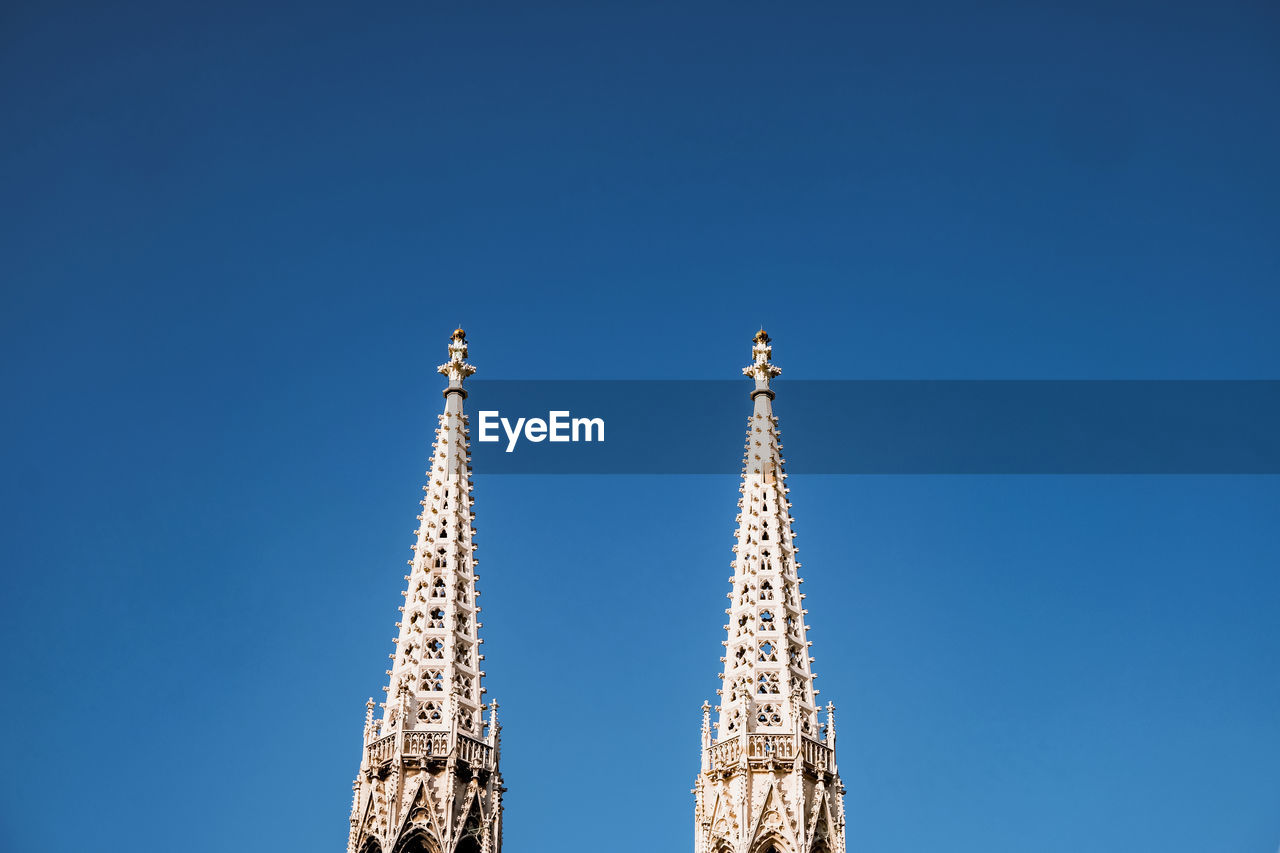 Low angle view of church towers against blue sky in vienna 