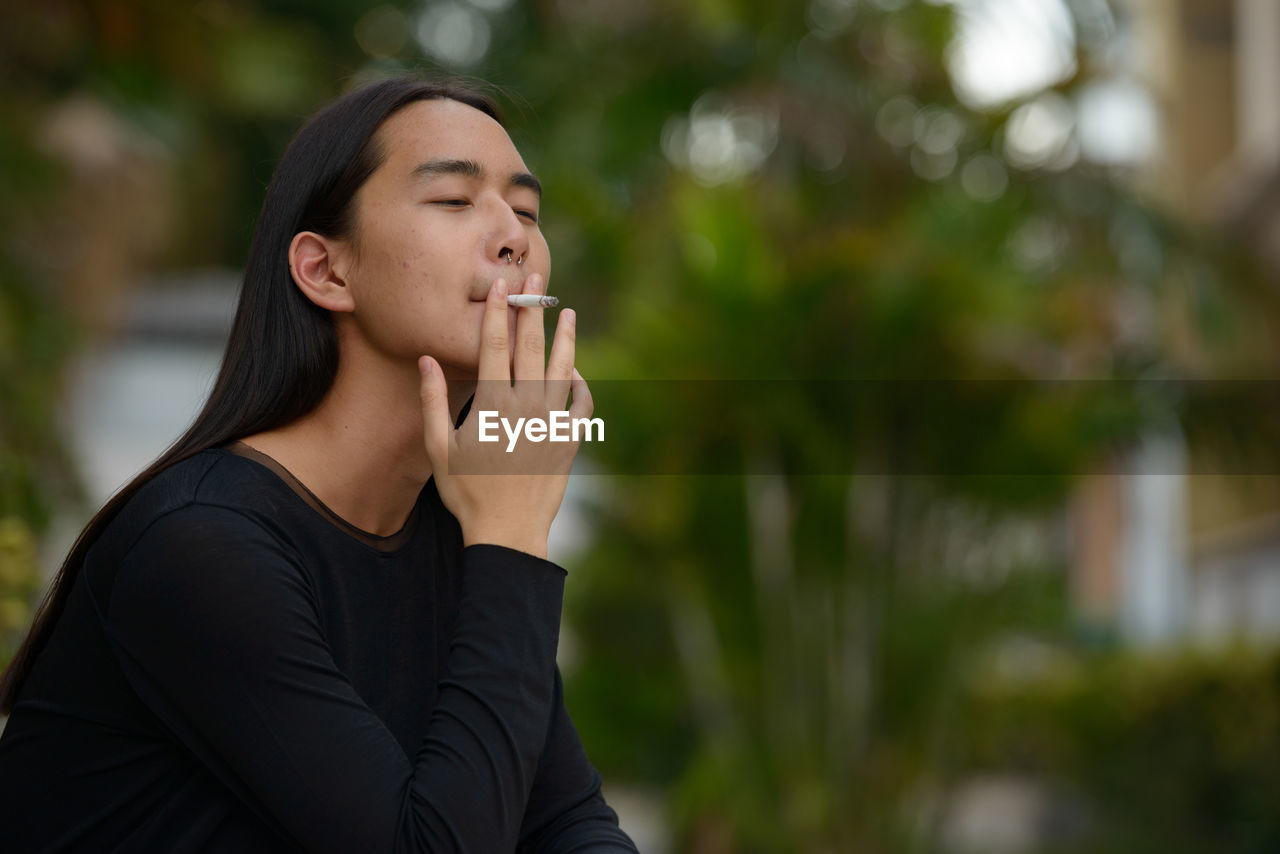 Young woman smoking cigarette outdoors