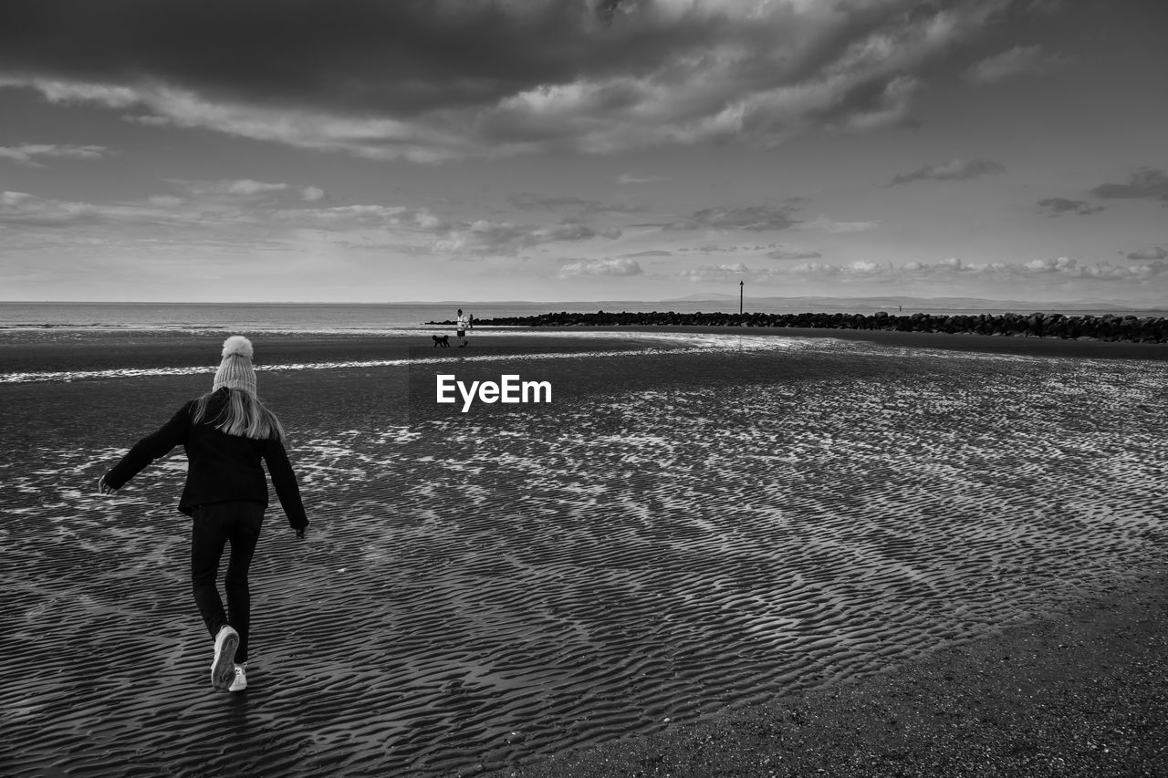 FULL LENGTH REAR VIEW OF MAN AT BEACH AGAINST SKY