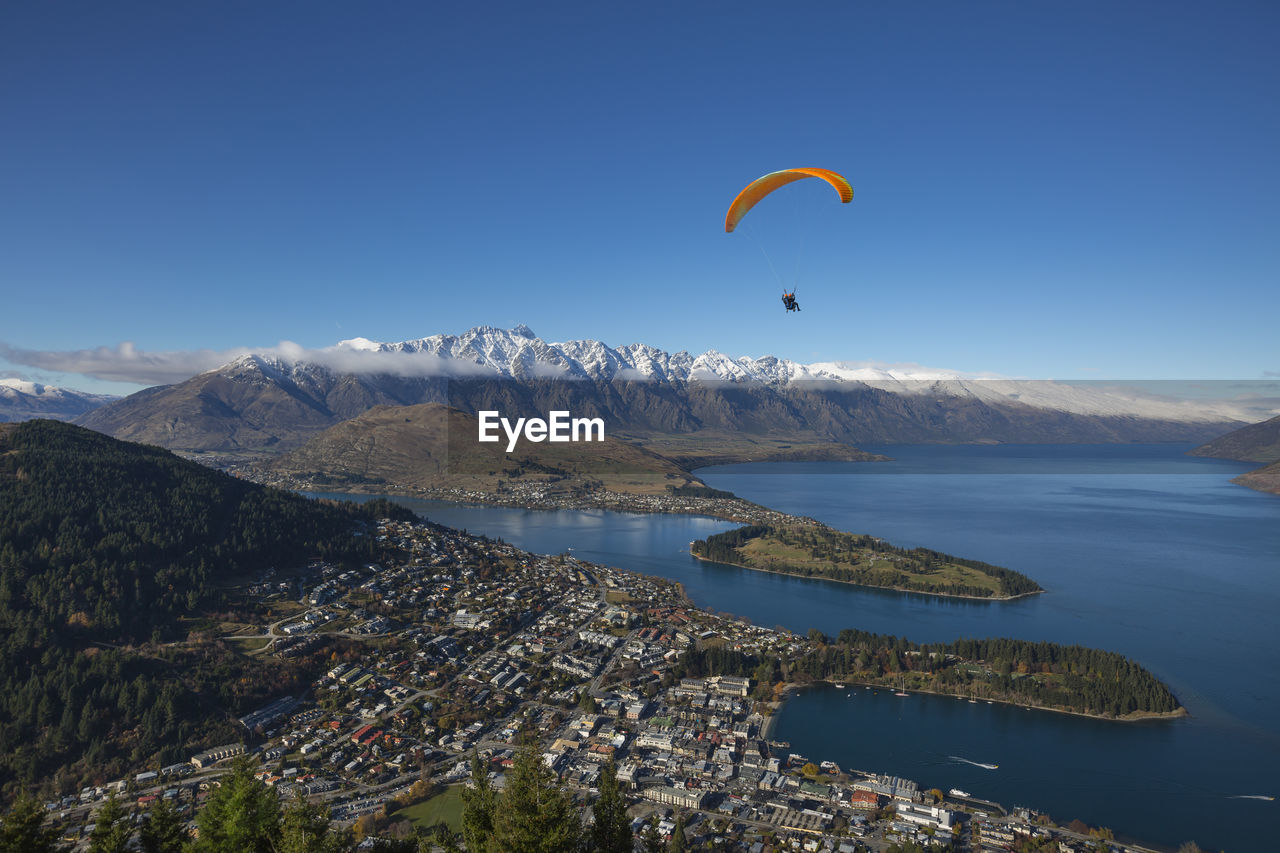 Person paragliding against clear blue sky