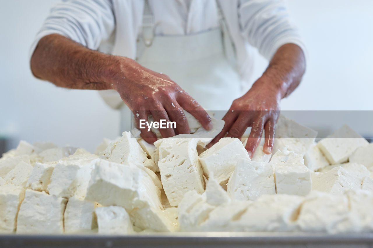 MIDSECTION OF MAN PREPARING FOOD IN CONTAINER