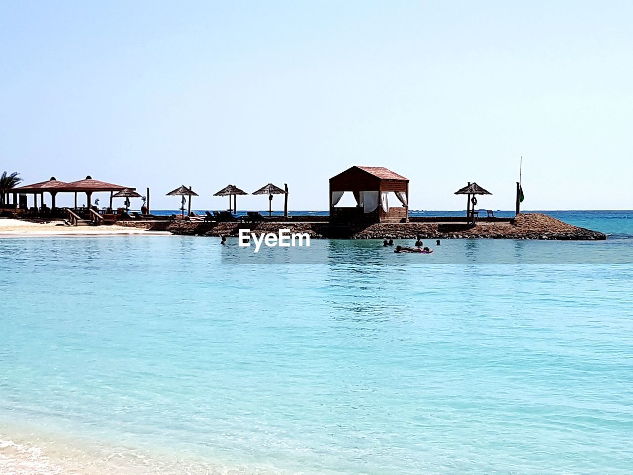 STILT HOUSE ON SHORE AGAINST CLEAR SKY