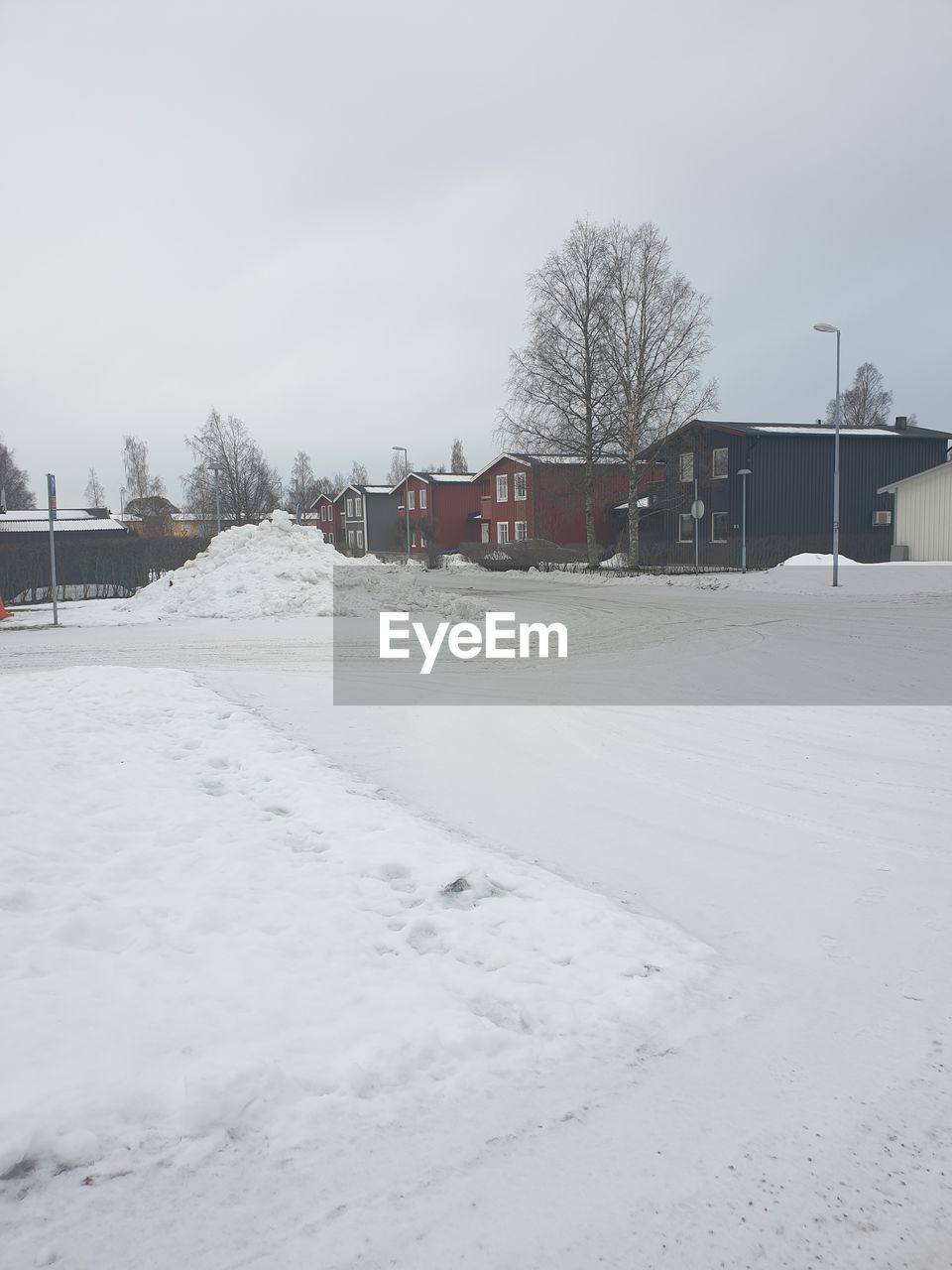 HOUSES ON SNOW COVERED FIELD BY BUILDINGS AGAINST SKY