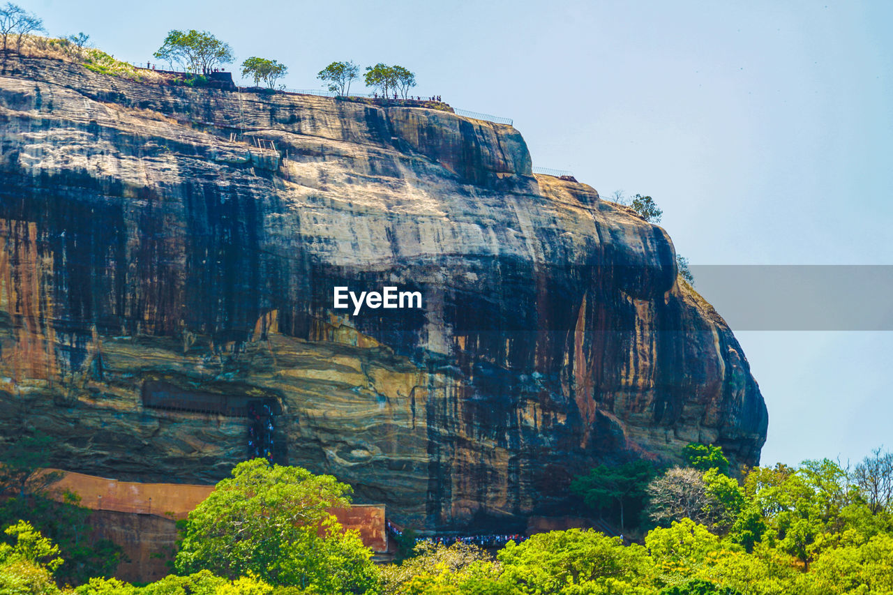 LOW ANGLE VIEW OF ROCK FORMATION AND TREES AGAINST SKY