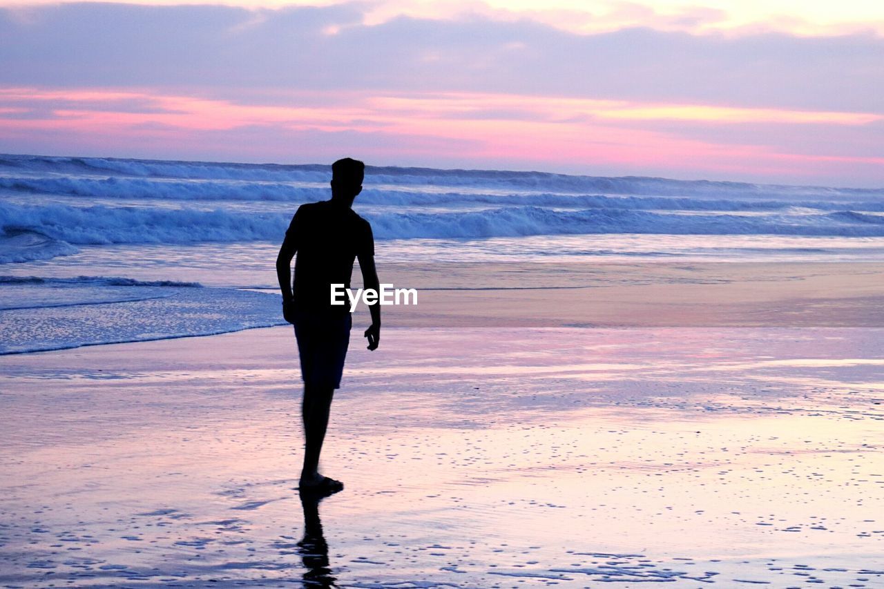 Solitary man on beach at sunrise