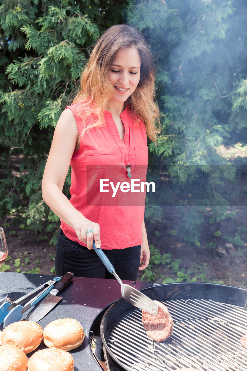 YOUNG WOMAN WEARING HAT STANDING ON BARBECUE