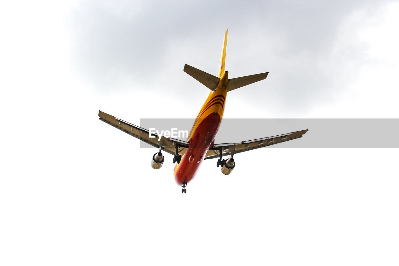 LOW ANGLE VIEW OF AIRPLANE IN MID-AIR AGAINST SKY