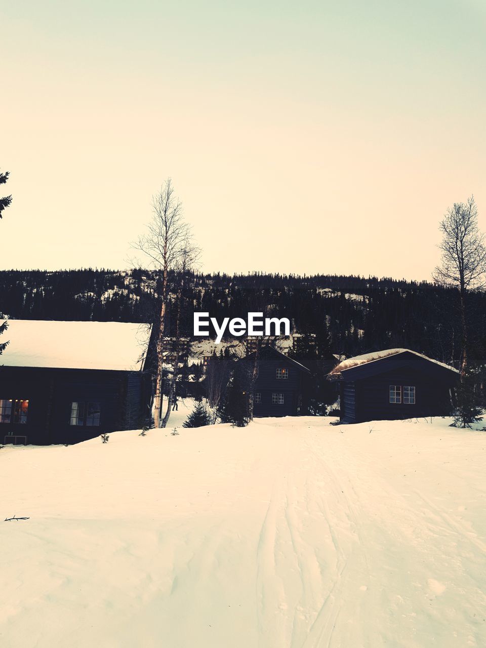 SNOW COVERED HOUSES BY BUILDING AGAINST CLEAR SKY