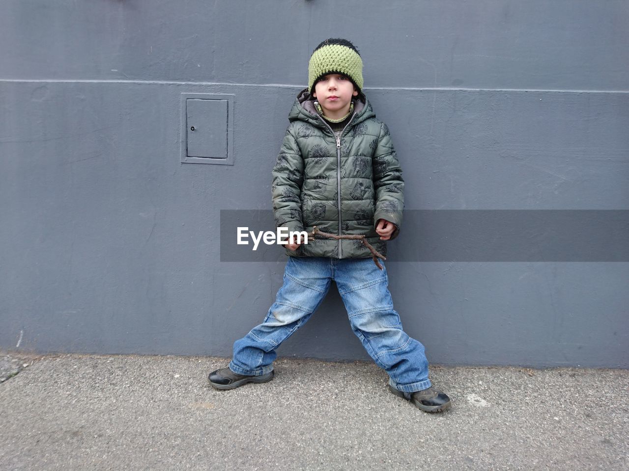 Full length portrait of boy standing against wall