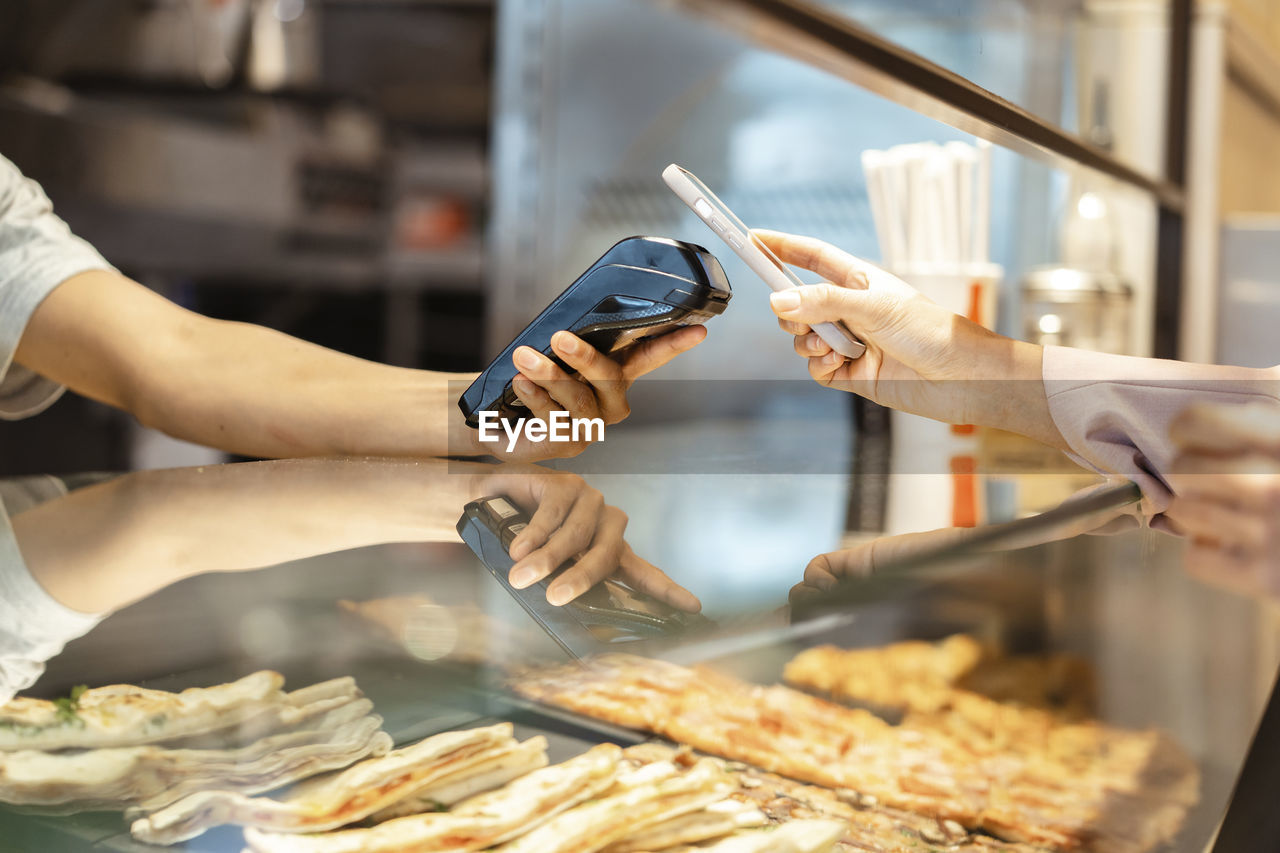 Hand of businesswoman making payment through smart phone on credit card reader