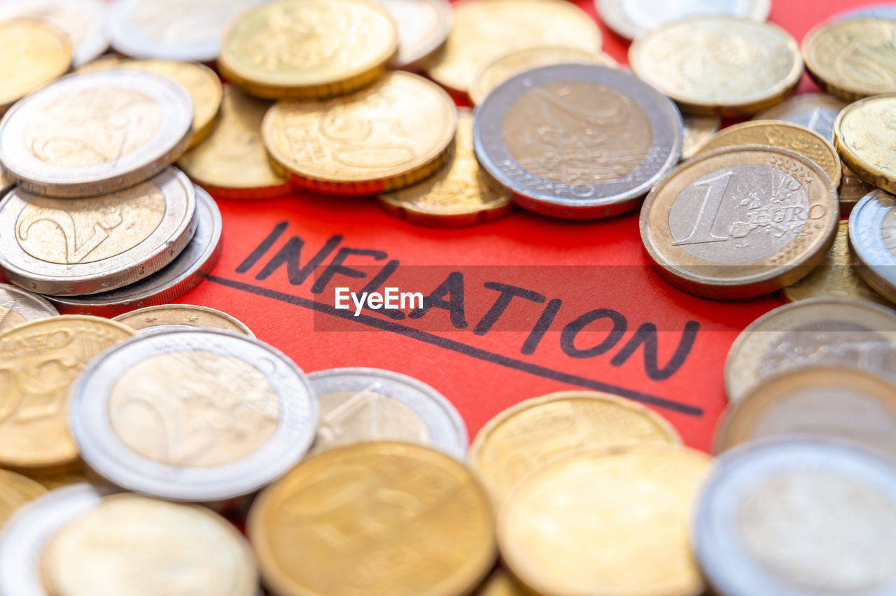 Word inflation on red surface, surrounded by euro coins. rising prices and economic repercussions.